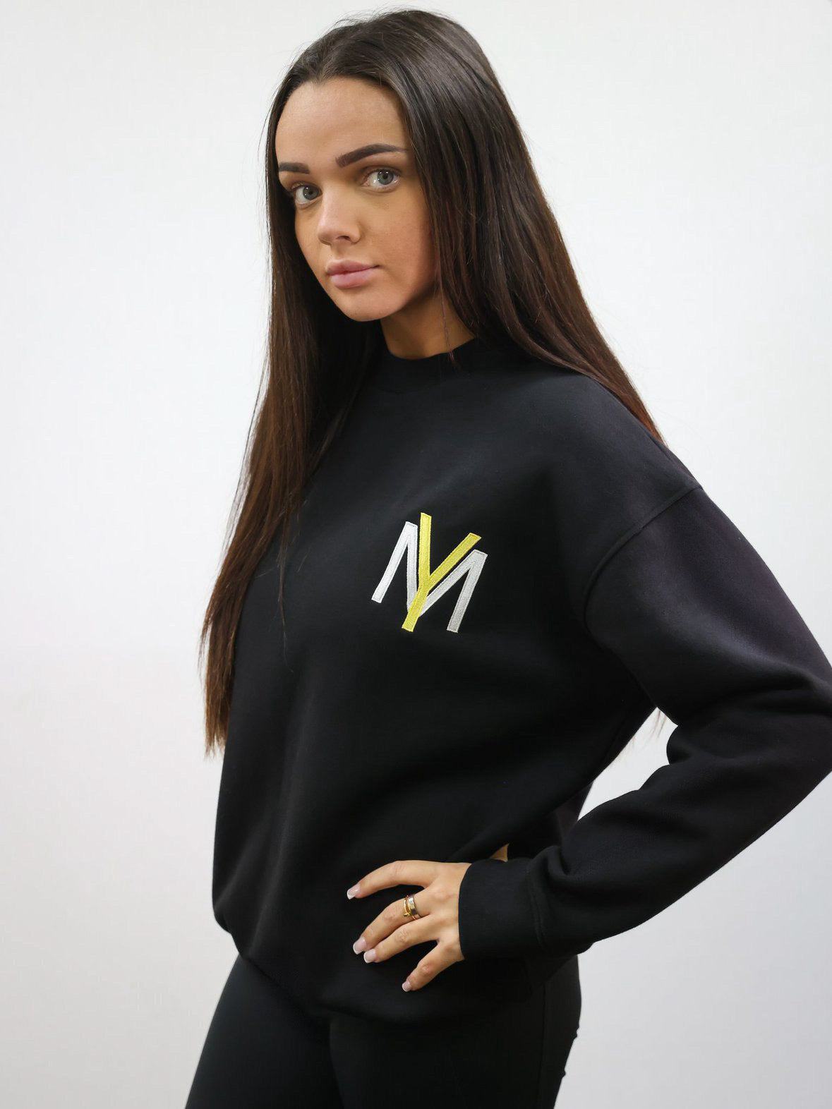 Black sweatshirt with embroidered yellow YM logo on a female model size small