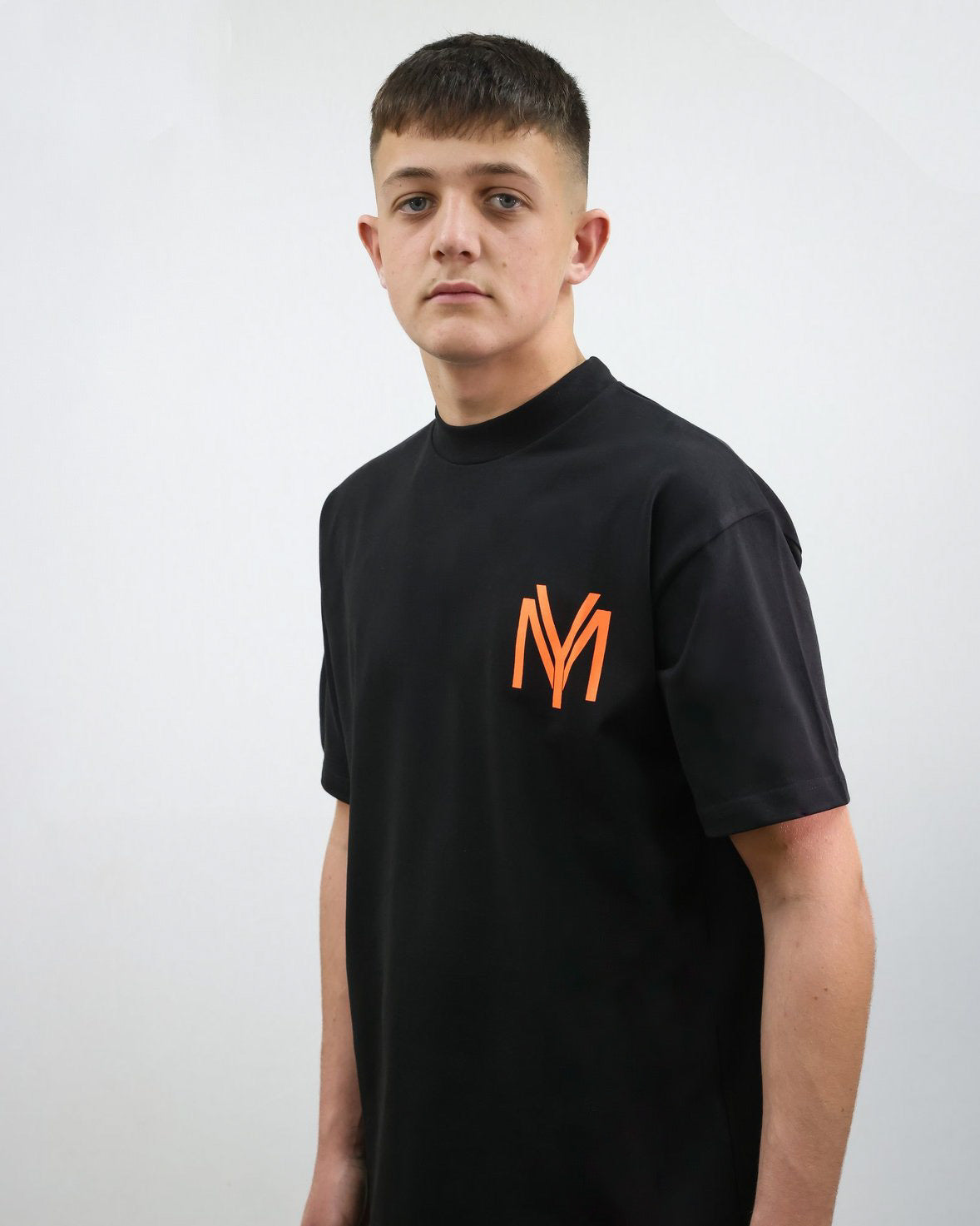 Black organic cotton oversized T-shirt with an orange YM logo print on the front on a male model size small