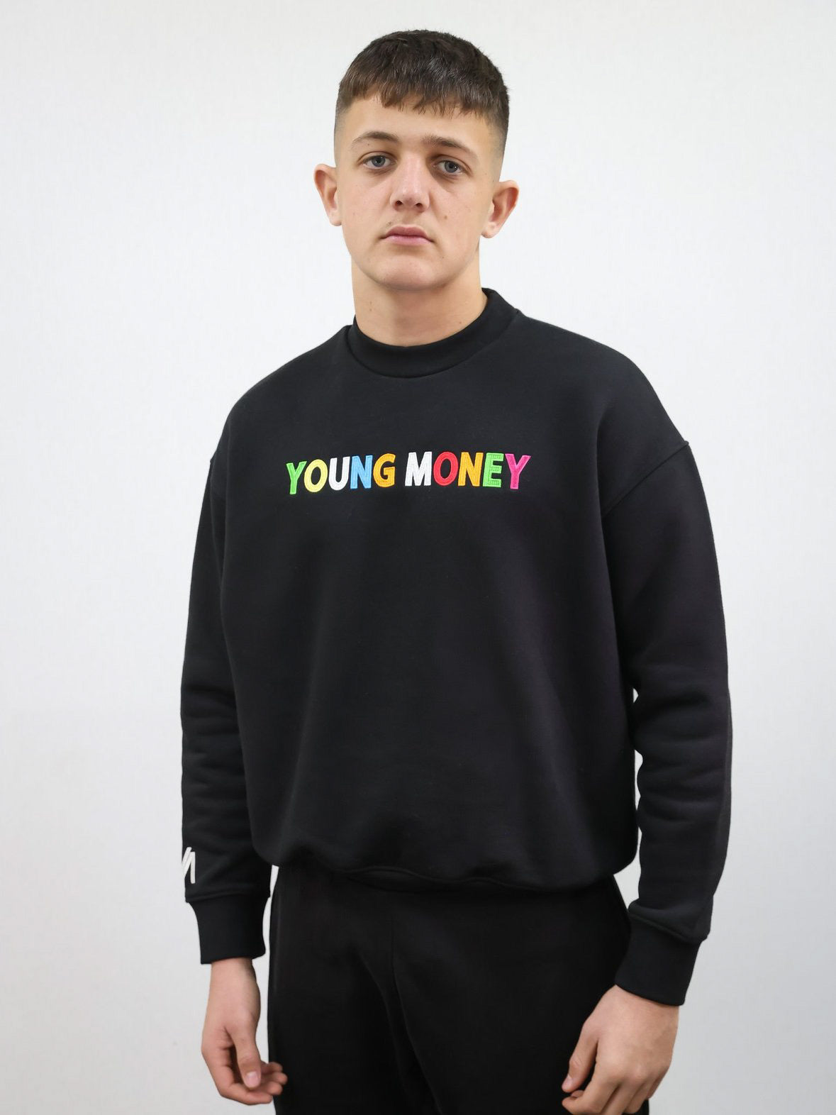 Black sweatshirt with a direct embroidered young money text in illuminous multicolours and white embroidered logo on the sleeve on a male model size medium