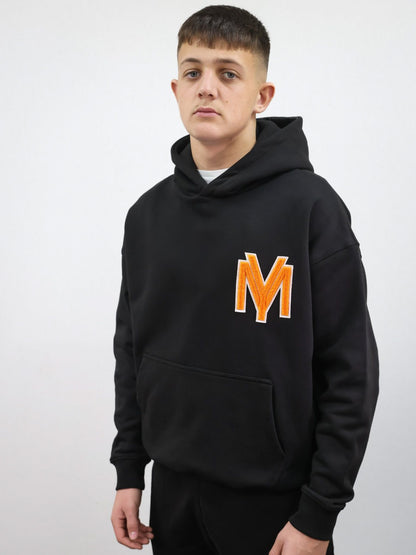 Premium organic cotton black hoodie with a raised fluffy embroidered YM logo on the chest in orange on a male model size medium