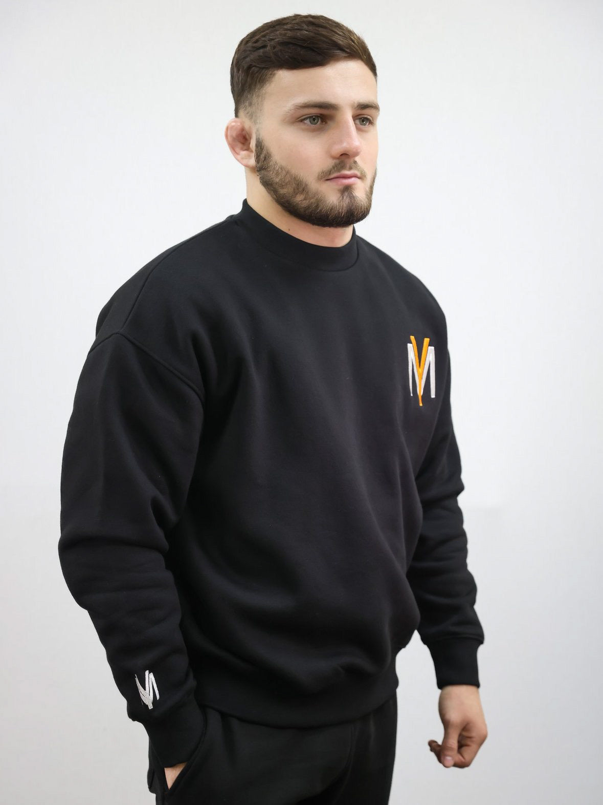 Black sweatshirt with embroidered orange YM logo on a male model size medium