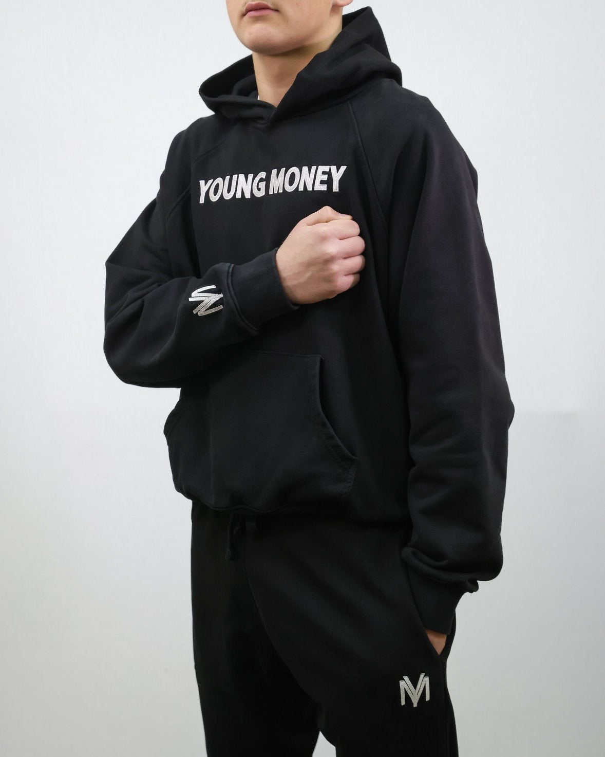 Black organic tracksuit hoodie and joggers with white embroidered texts and logos on a male model size small