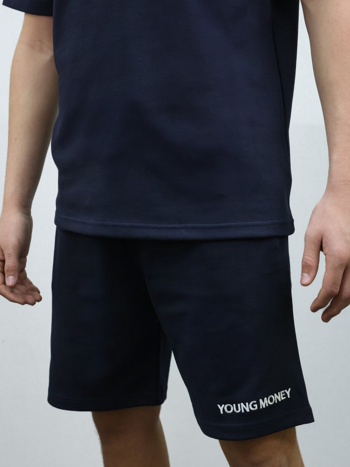 Navy relaxed fit shorts with embroidered young money text on a male model with matching T-shirt set size medium