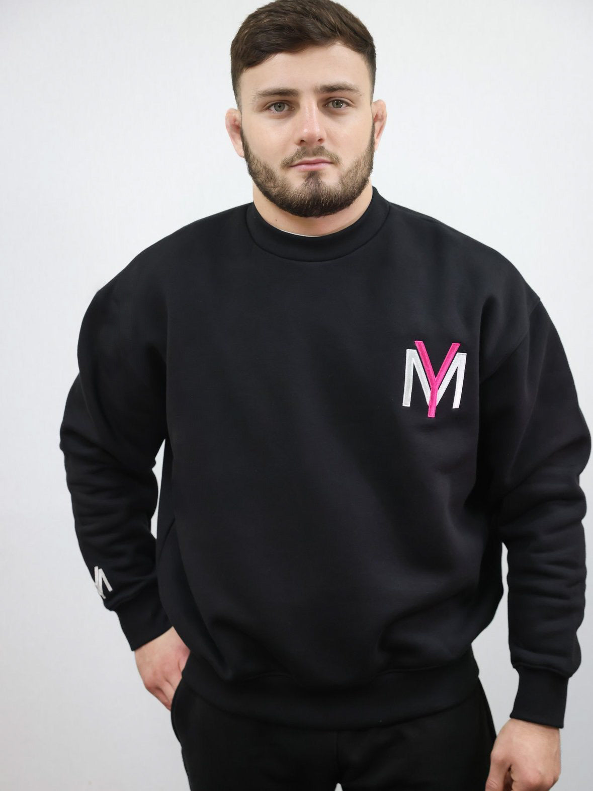 Black sweatshirt with embroidered pink YM logo on a male model size medium