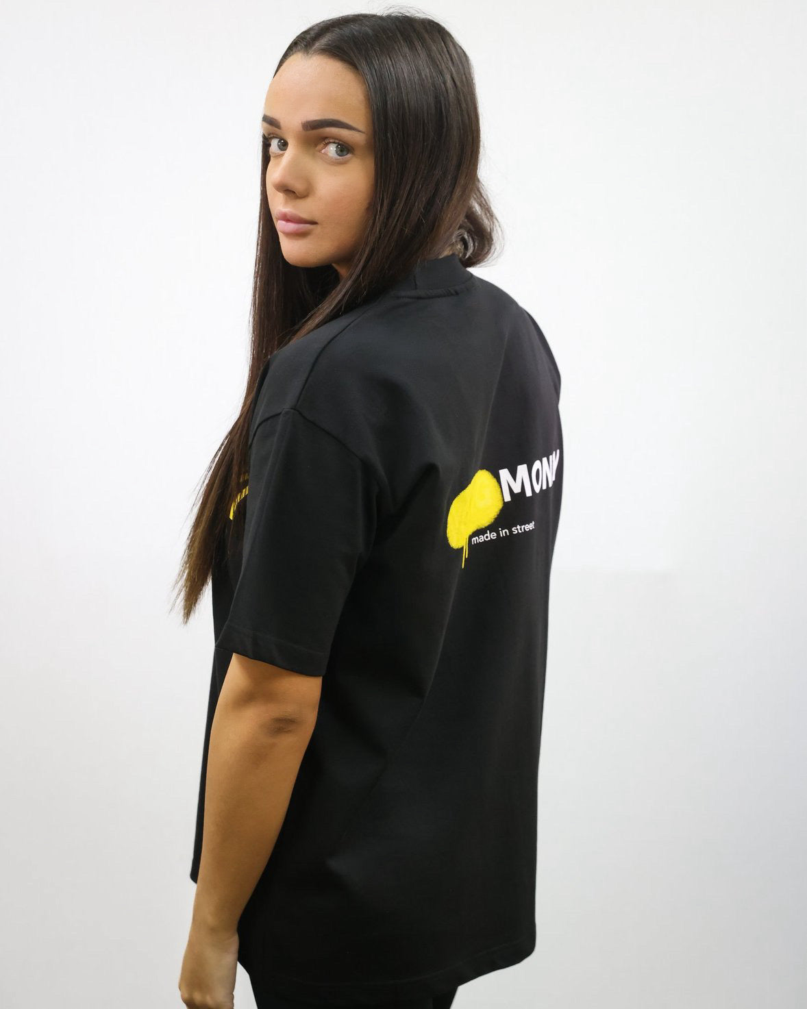 Black organic cotton oversized T-shirt with a yellow spray paint graphic on the back on a female model size XS