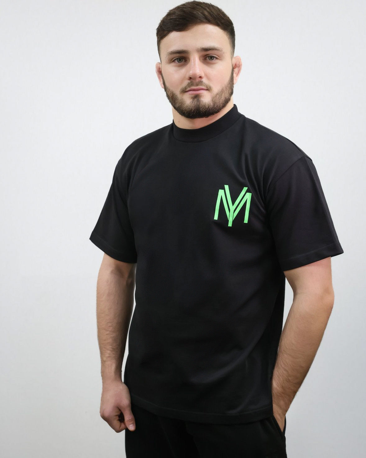 Black organic cotton oversized T-shirt with a green YM logo print on the front on a male model size medium